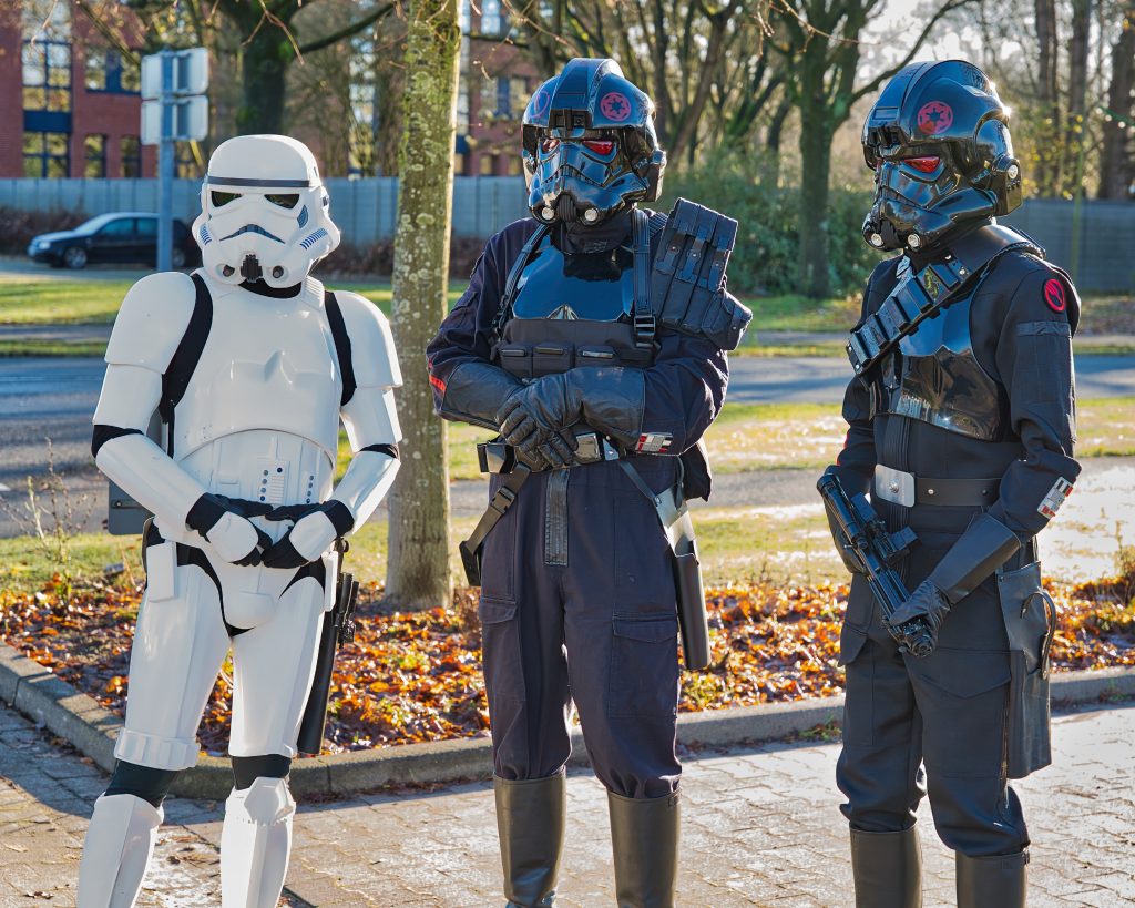 Drei Star-Wars-Cosplayer in Stormtrooper- und Pilotenrüstungen posieren im Freien bei Tageslicht.