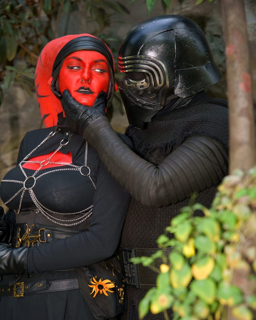 Star Wars Cosplayfoto mit zwei Charakteren der dunklen Seite – intensive Szene mit maskiertem Krieger und roter Kriegerin, professionelle Cosplay Fotografie.