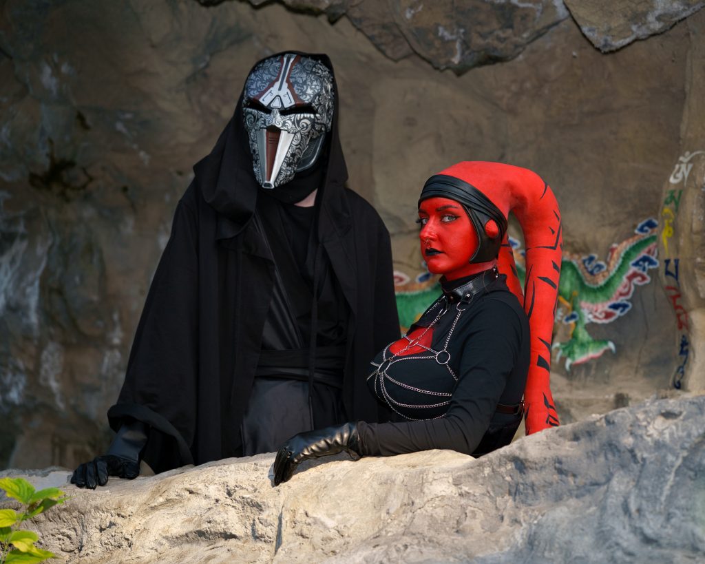 Cosplayfoto mit zwei Star Wars Charakteren – dunkle Sith-Figur mit Maske und rote Kriegerin, professionelle Cosplay Fotografie.