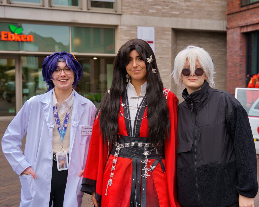 Drei Cosplayer in kreativen Kostümen posieren in einer Stadtumgebung – professionelle Cosplay Fotografie mit urbanem Flair und detailreichen Charakteren.