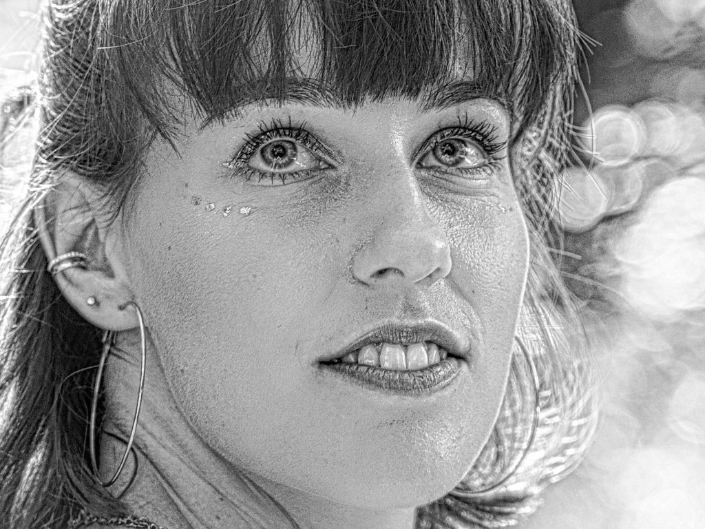 Schwarz-Weiß-Portrait einer Frau mit funkelnden Augen im natürlichen Licht – künstlerische Porträt Fotografie.