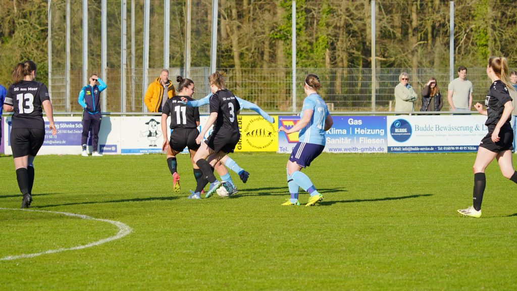 Sportfotografie eines Frauenfußballspiels – Spielerinnen im Zweikampf um den Ball im Mittelfeld, voller Dynamik und Konzentration.