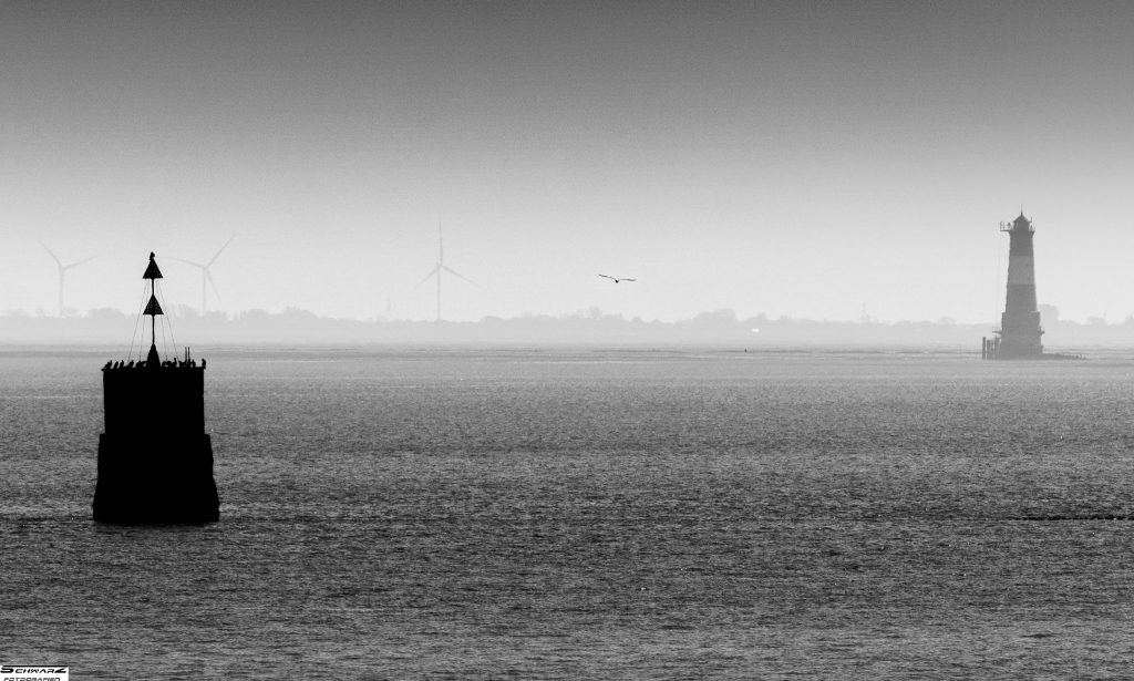 Schwarz-Weiß-Fotografie eines Leuchtturms und Seezeichens auf dem Meer – stimmungsvolle Landschaft Fotografie.