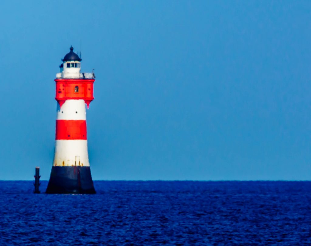 Rot-weiß gestreifter Leuchtturm in der Nordsee bei klarem Himmel – maritime Landschaft Fotografie.