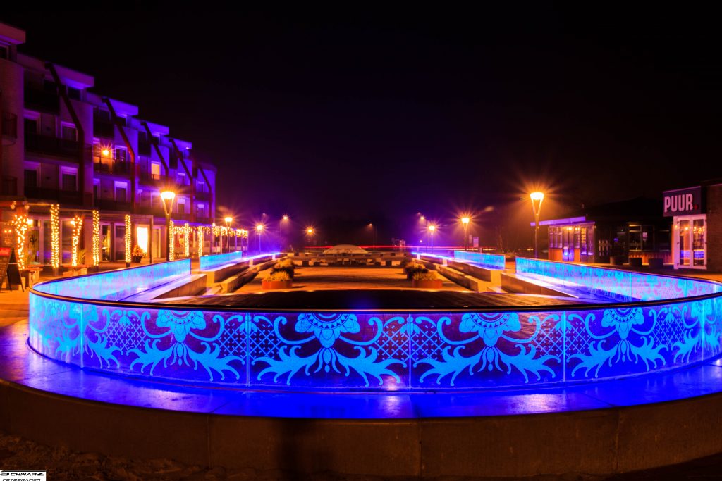 Beleuchtete Stadtanlage mit blauen Glaselementen und moderner Architektur bei Nacht – professionelle Landschaft Fotografie