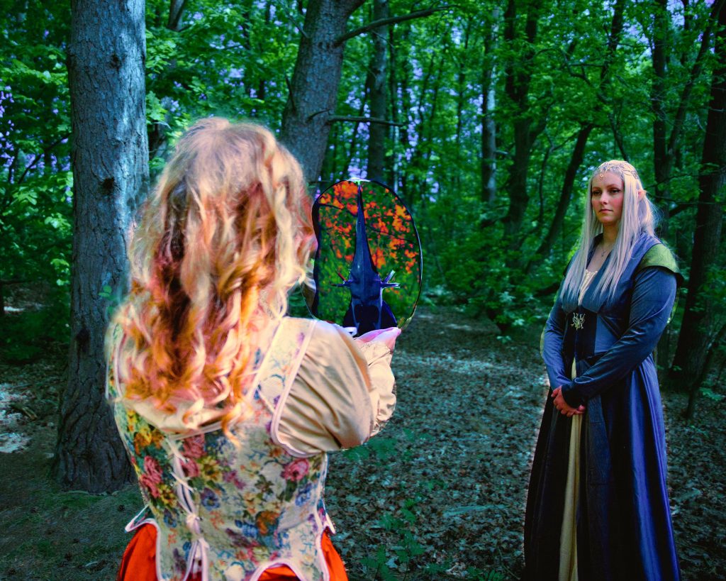 Fantasyfoto zweier Frauen in mittelalterlichen Gewändern im Wald – magische Szene mit leuchtendem Spiegel und märchenhafter Atmosphäre.