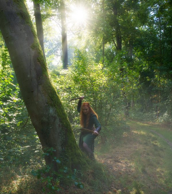 Fantasy Foto einer Waldkriegerin mit Bogen und Dolch im Sonnenlicht – kreative Fantasy Fotografie im Wald.