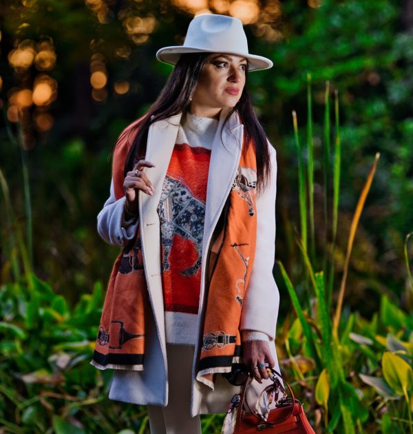 Portraitfotografie einer eleganten Frau im modischen Outfit mit weißem Hut im warmen Abendlicht.