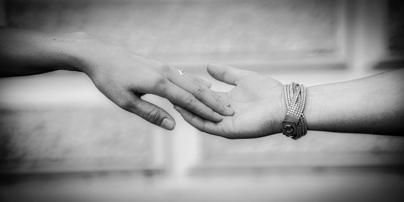 Zwei Hände, die sich zärtlich berühren – emotionale Schwarz-Weiß-Portraitfotografie über Nähe und Vertrauen.