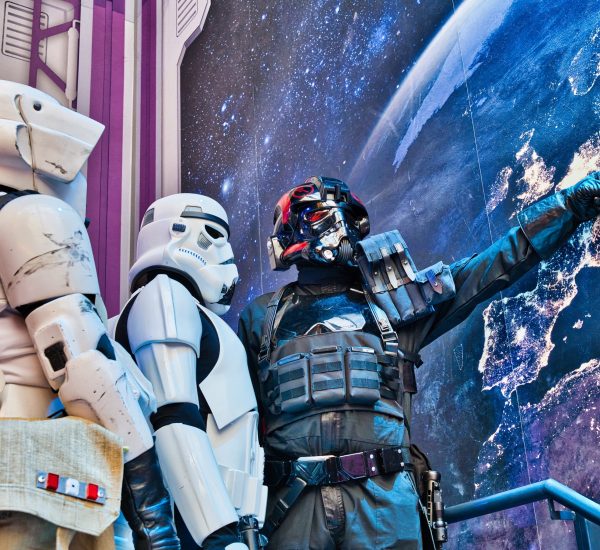 Drei Cosplayer in Stormtrooper-Rüstungen posieren vor einer Weltraumkulisse, einer zeigt auf eine Karte der Erde. Cosplay Fotografie mit Science Fiction Atmosphäre